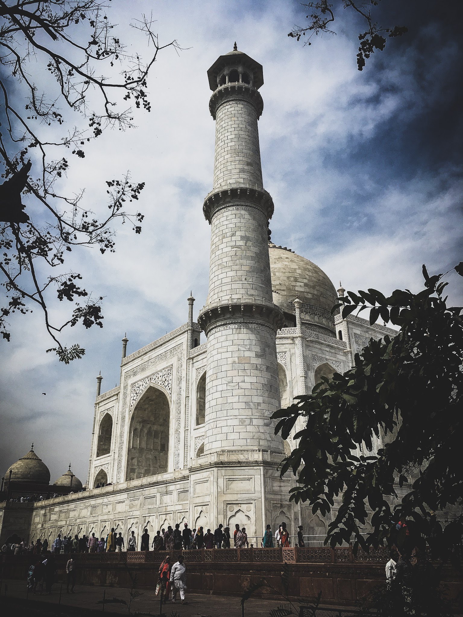 The Taj Mahal framed by trees beneath a dramatic sky